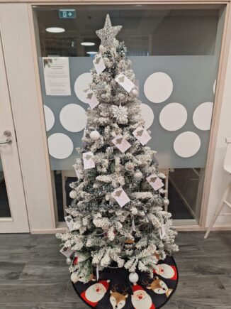 Koristettu joulukuusi, jonka oksilla lappuja lasten lahjatoiveista