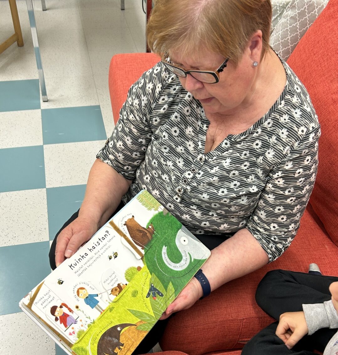 Nainen lukemassa kuvakirjaa lapselle