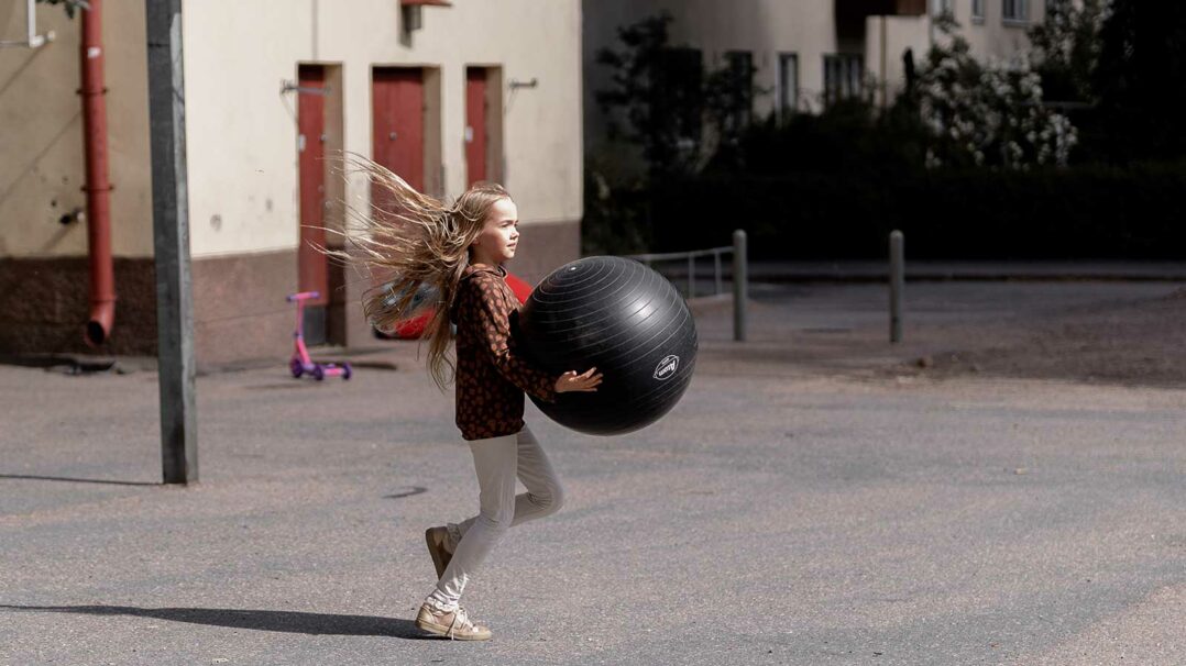 Lapsi juoksee pallo käsissään ulkona.