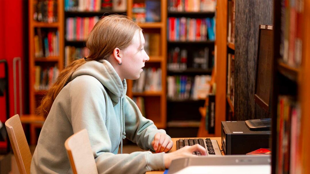 Nuori tietokoneella kirjastossa