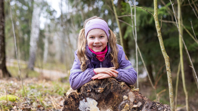 Lapsi makoilee iloisena puunrungolla metsässä
