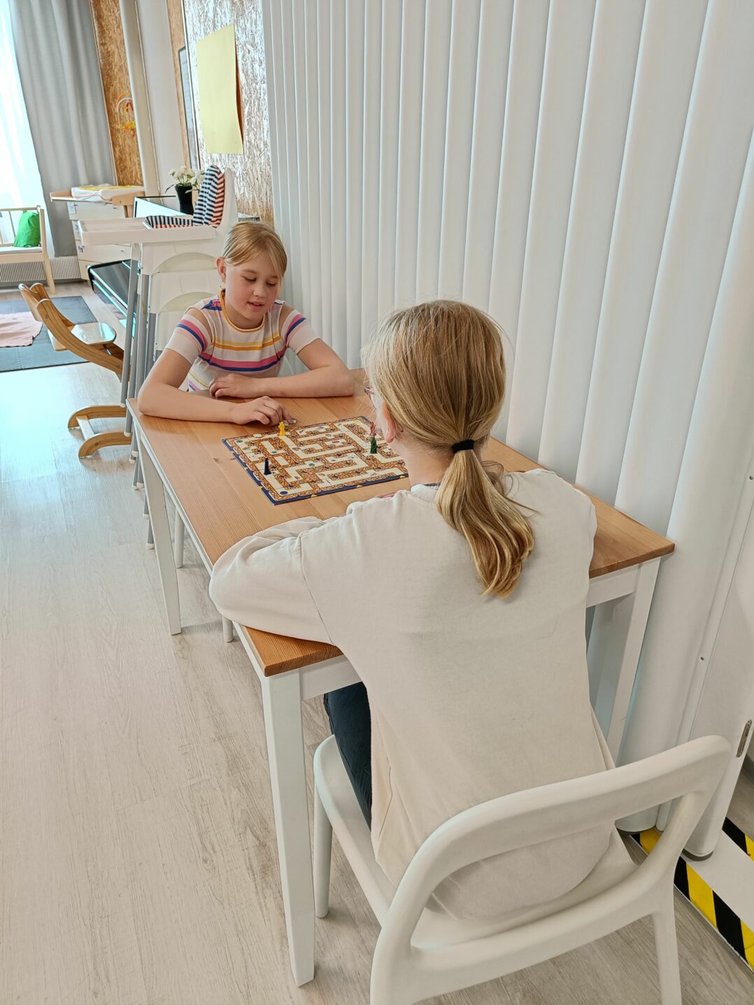 2 alakouluikäistä lasta pelaa muuttuvaa labyrinttiä