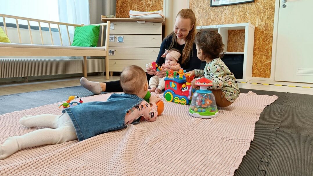 Äiti ja 3 lasta leikkii lattialla