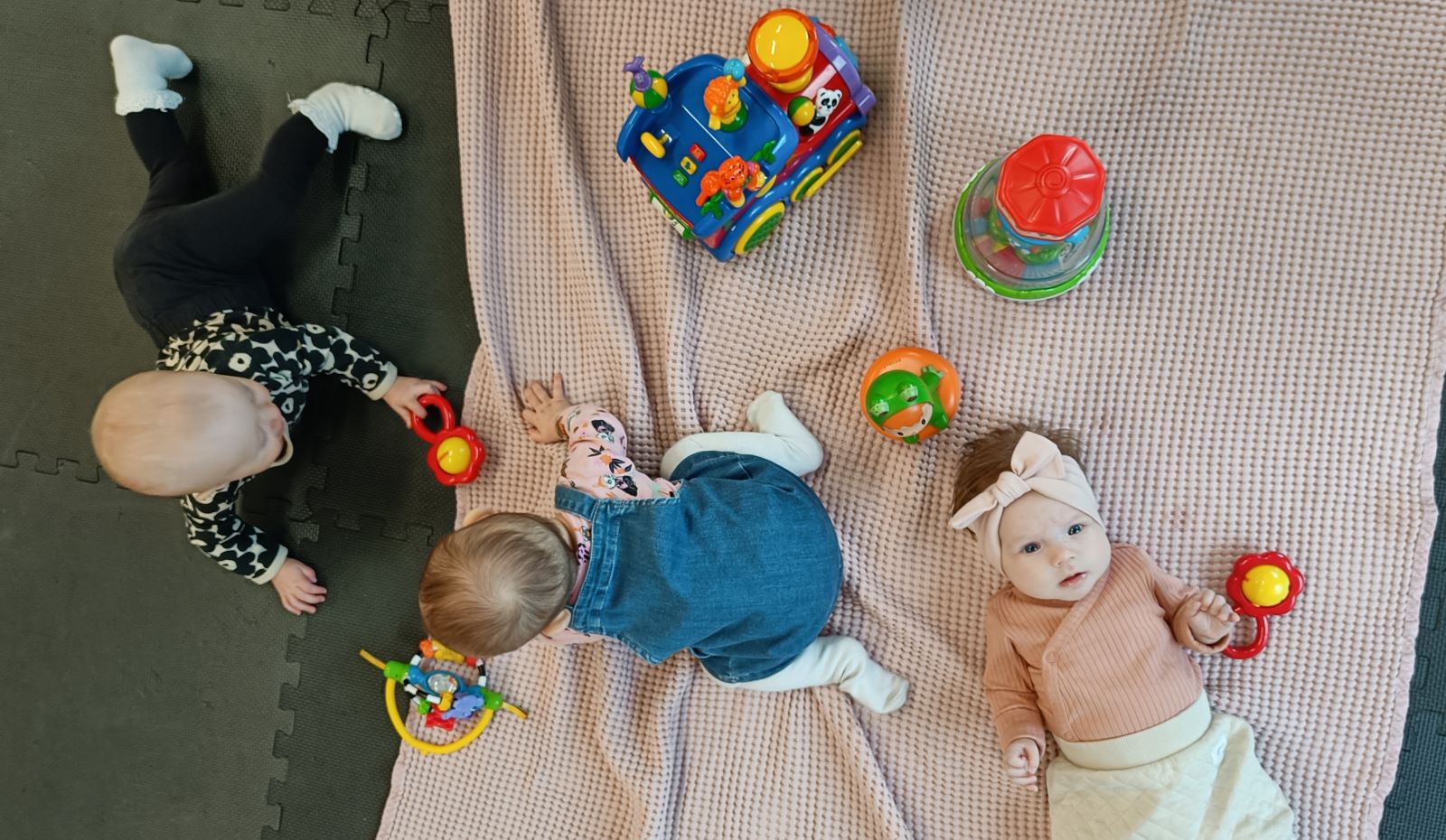 3 vauvaa lattialla lelujen kanssa
