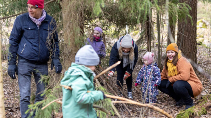 Aikuiset ja lapset touhuavat yhdessä metsässä