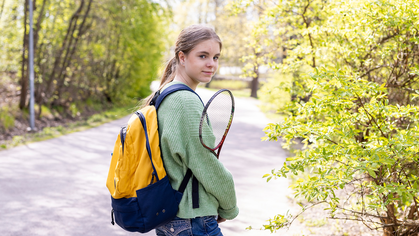 Lapsi repun ja sulkapallomailan kanssa seisoo ulkona