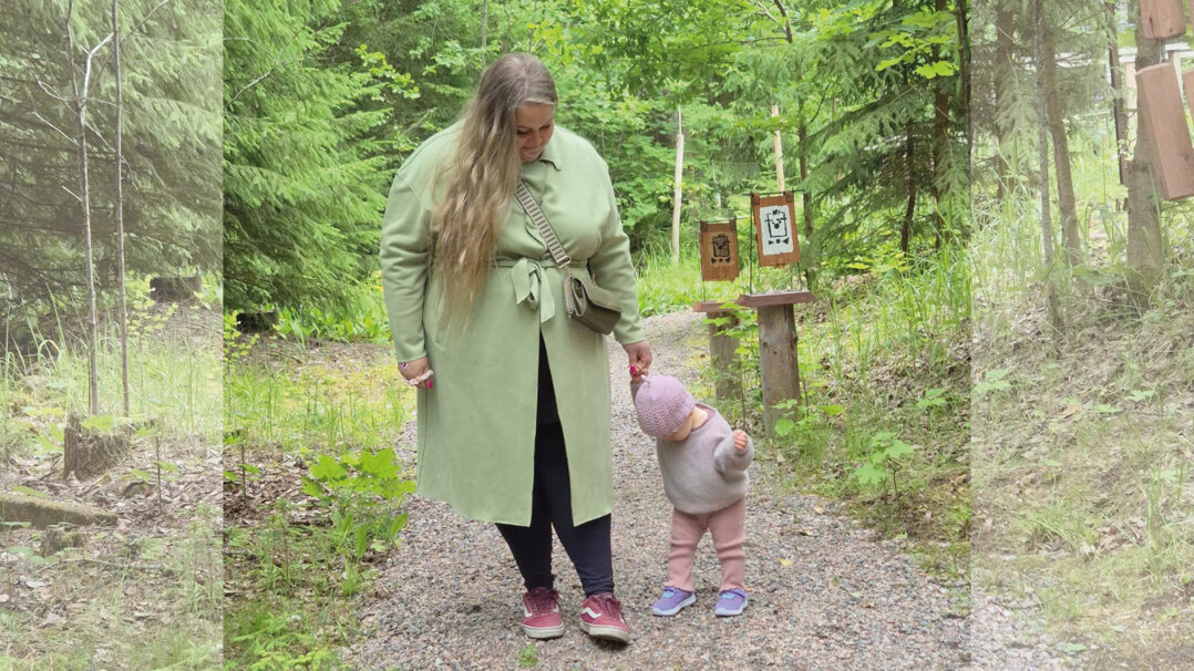 Äiti ja lapsi kävelevät käsikkäin metsäpolulla