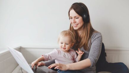 Aikuinen nainen lapsi sylissä katsovat tietokonetta
