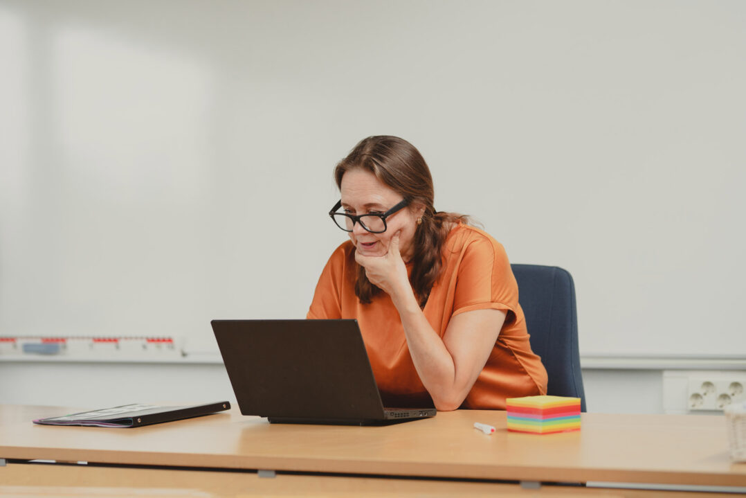 Kuvituskuva, jossa opettaja työskentelee kannettavan tietokoneen ääressä.