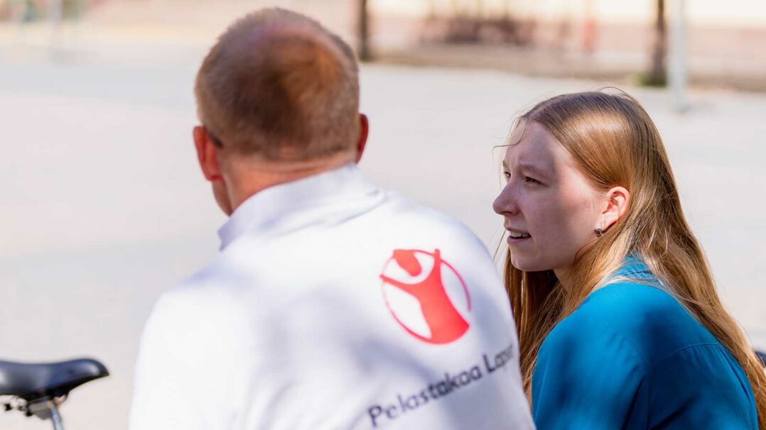 Pelastakaa Lasten vapaaehtoinen juttelee nuoren kanssa ulkona