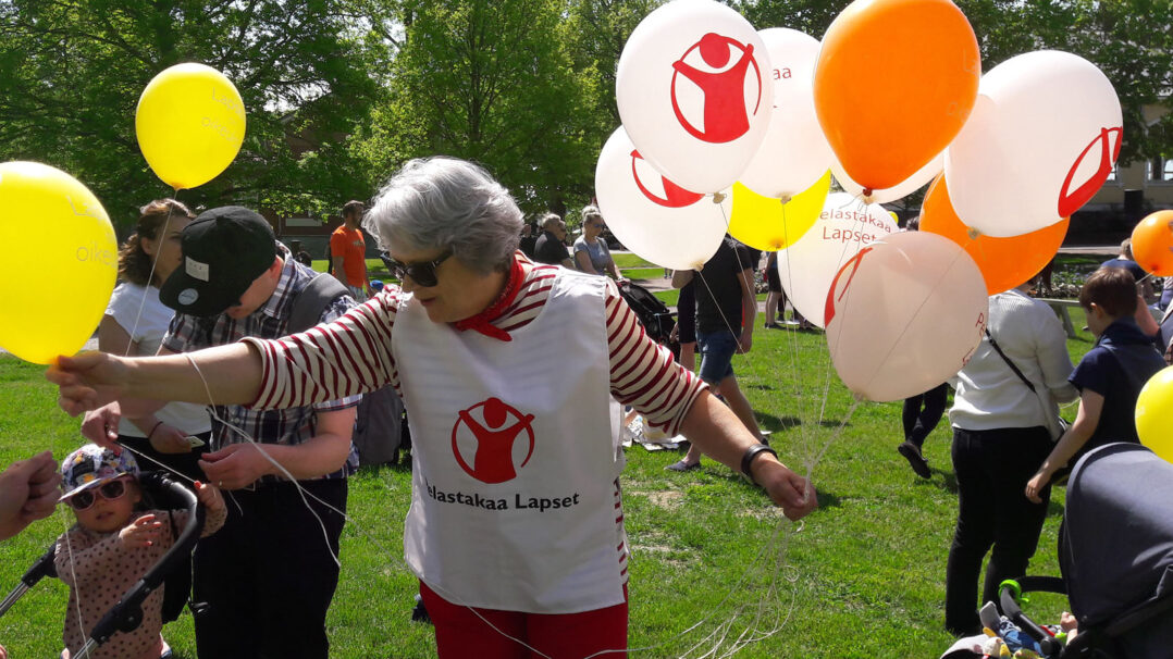 Paikallisyhdistyksen vapaaehtoinen jakaa lapsille ilmapalloja perhetapahtumassa