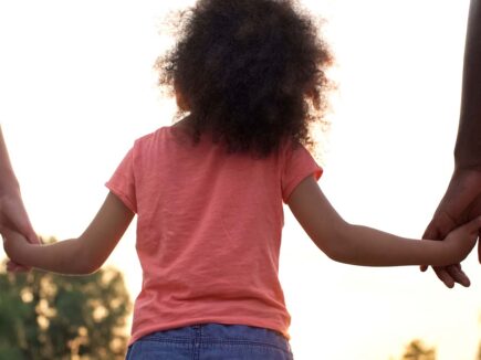 A child holding their parents' hands.