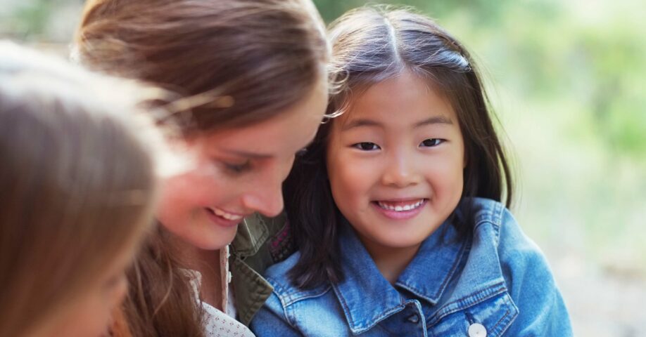 aasialainen tyttö istuu aikuisen naisen sylissä ja hymyilee
