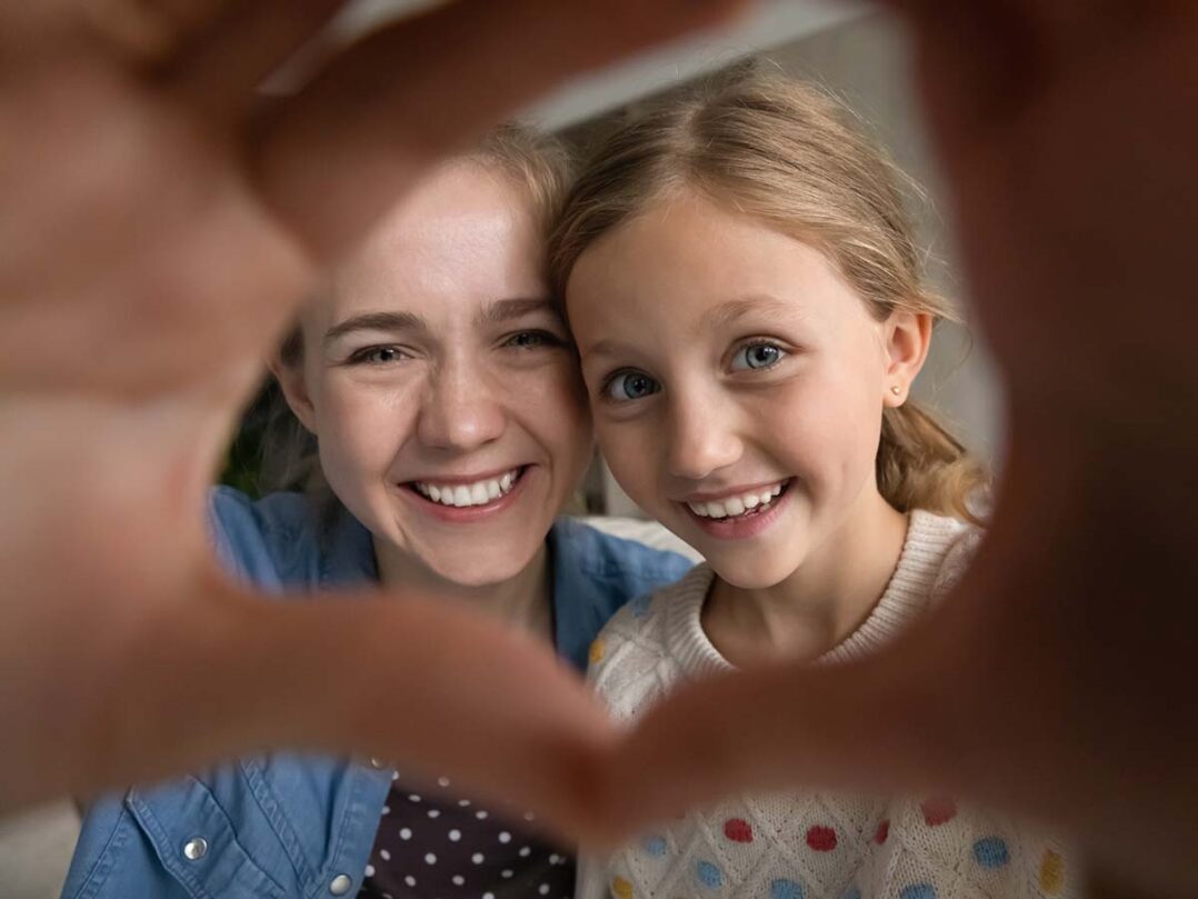 lapsi ja nainen ottavat selfietä ja muodostavat käsillään sydämen.