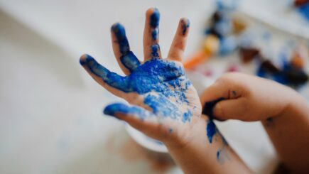 pienen lapsen käsi, jossa on sinistä maalia