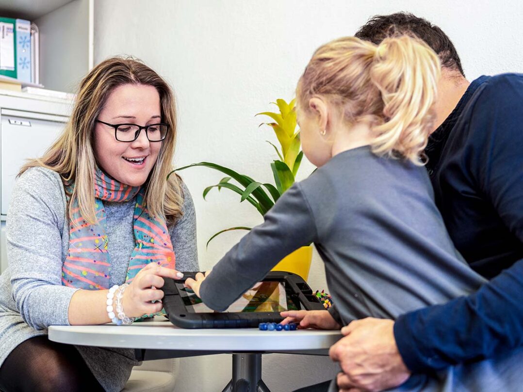 nainen näyttää tietokoneelta isälle ja lapselle