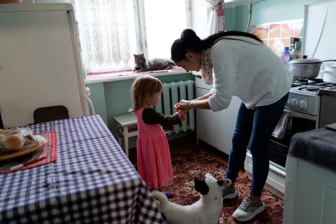 Keittiössä ukrainalainen Oksana-äiti tutkii lapsensa 3-vuotiaan lapsensa kättä.