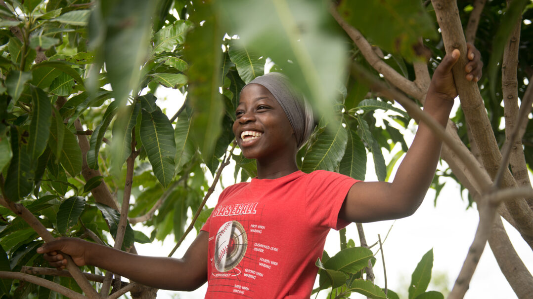 A girl under a tree smiling.