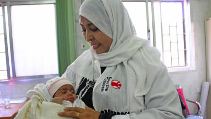 Pelastakaa Lasten työntekijä pitää sylissään vauvaa Jemenissä.