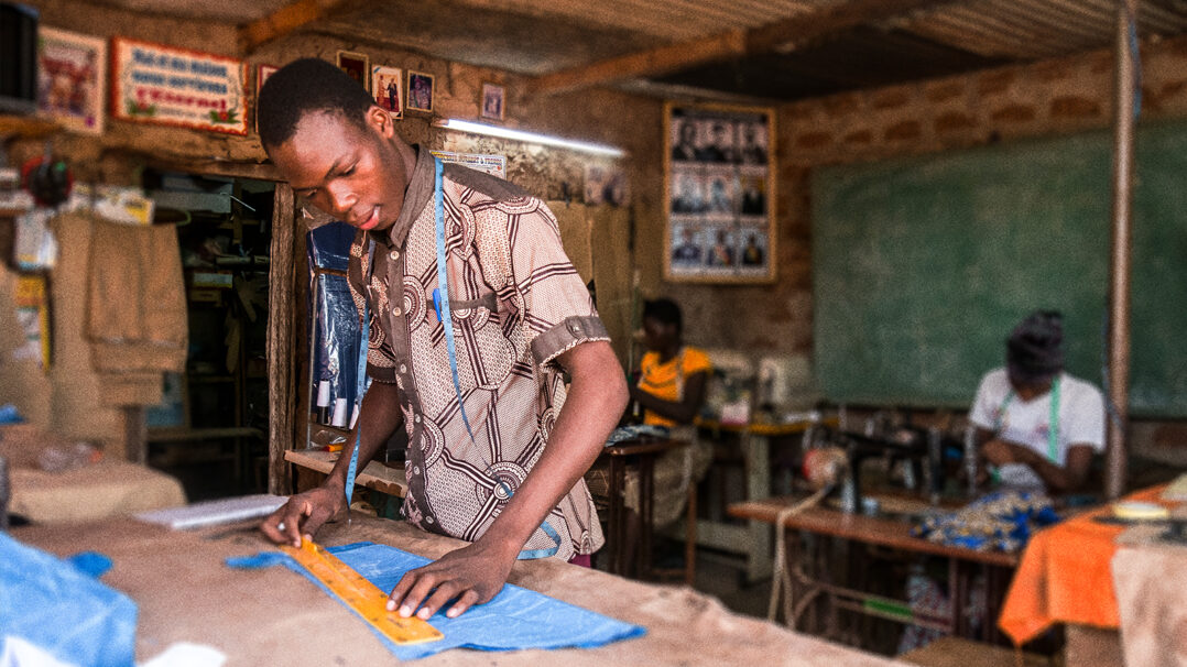 Nuori mies mittaa tekstiiliä ompelua varten Burkina Fasossa työpaikallaan.