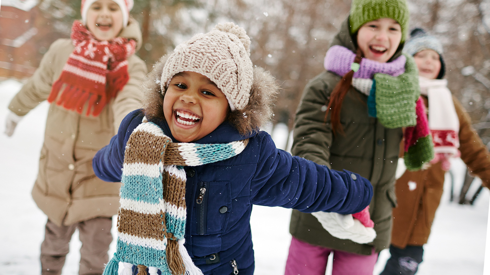 Lapsia nauraa ulkona talvisessa maisemassa.