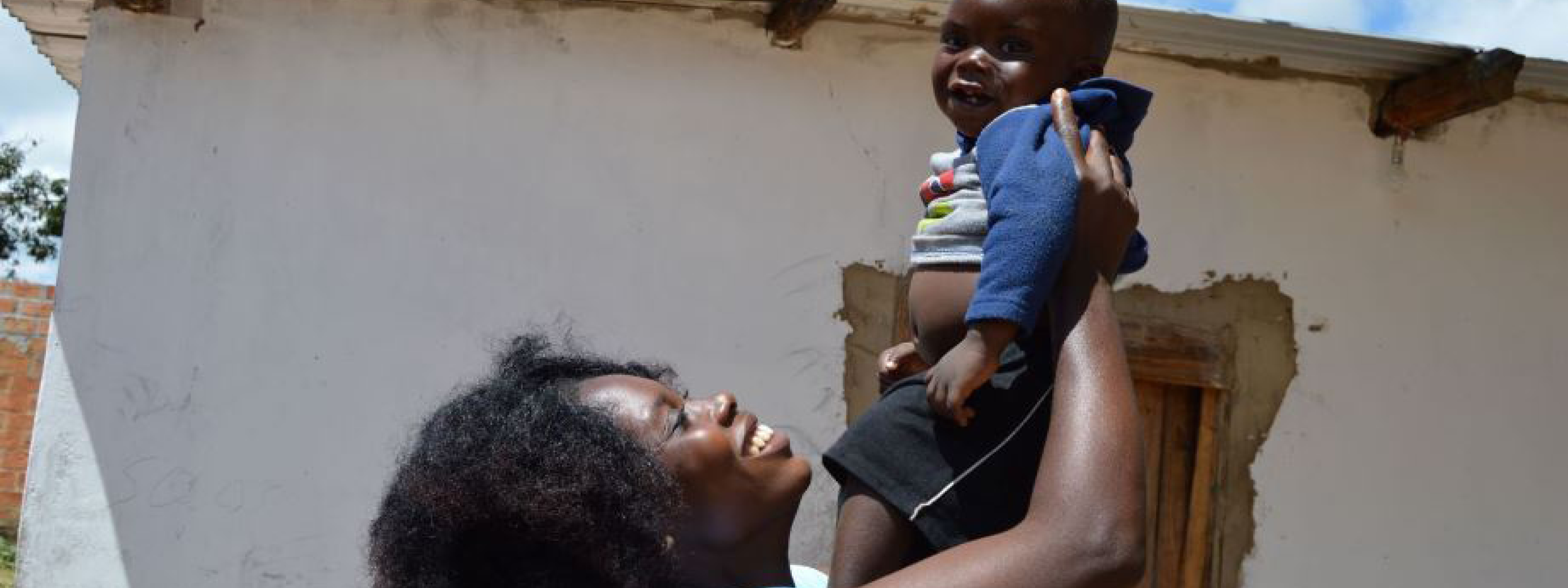 Äiti nostaa lasta ilmaan kadulla Sambiassa.