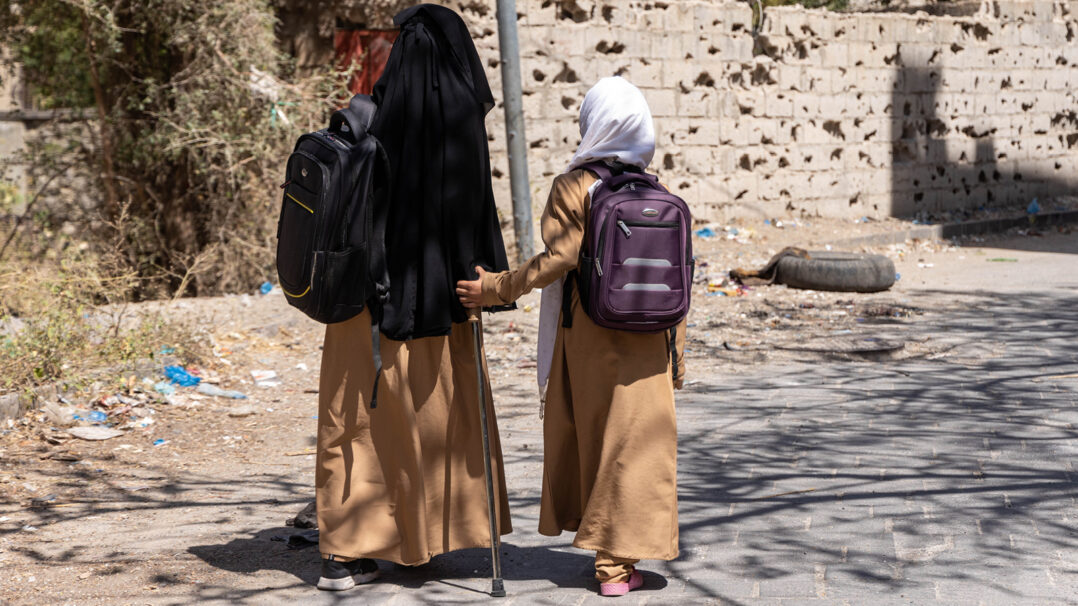Kaksi lasta kävelemässä kadulla reput selässä Jemenissä.