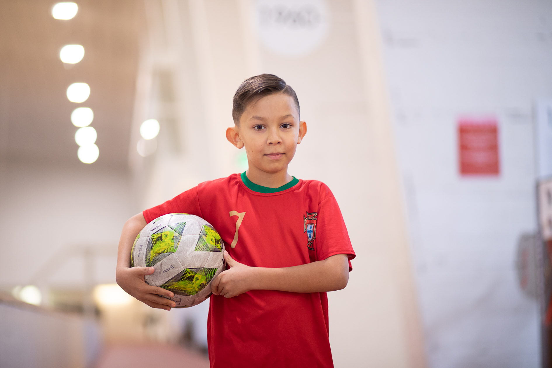 Poika pitelee jalkapalloa käsissä.