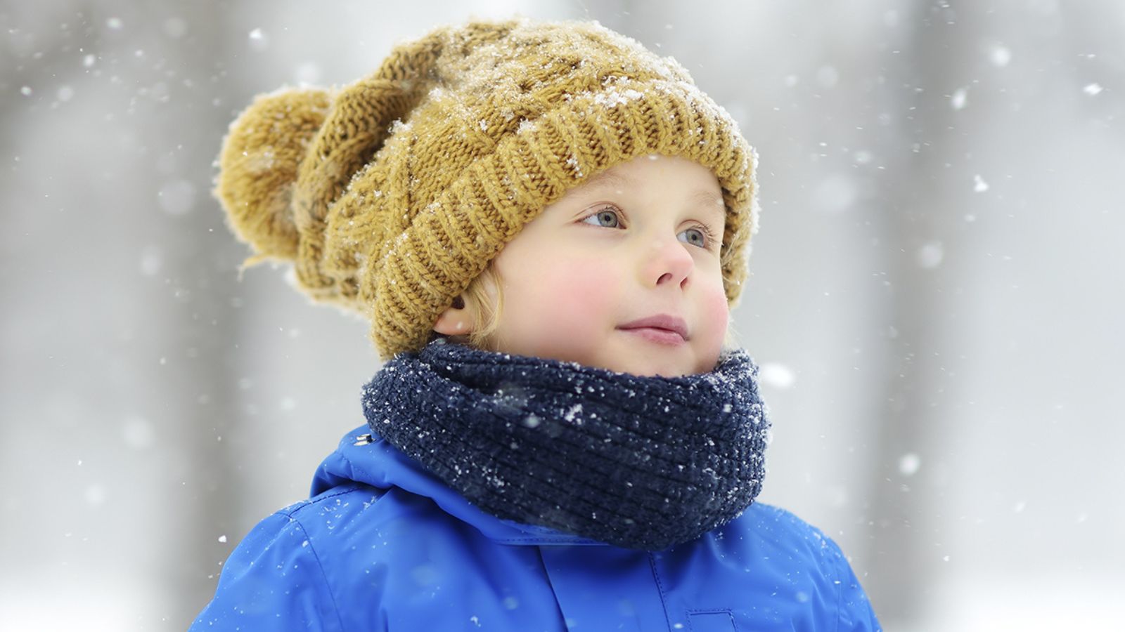 Pieni poika lumisateessa pipo päässä.