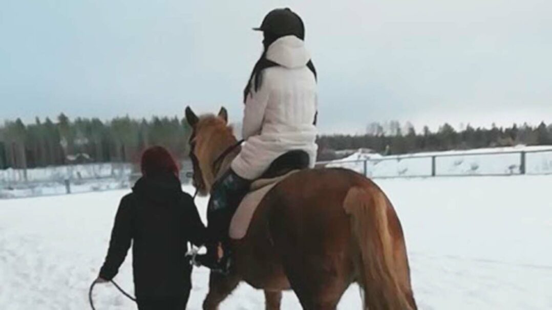 Valokuva tyttäasukkaasta, joka ratsastaa hevosella.