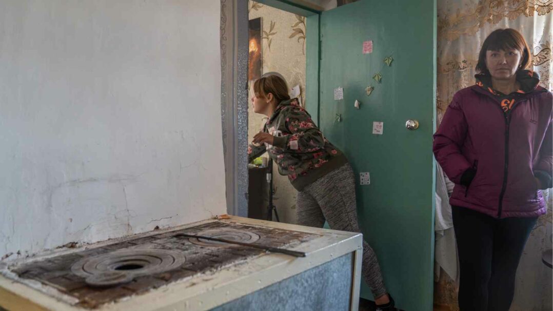 Kuvassa Anna, 12, ja Maryna, 39, vanhan hellan vieressä, jolla he lämmittävät talonsa Ukrainassa.