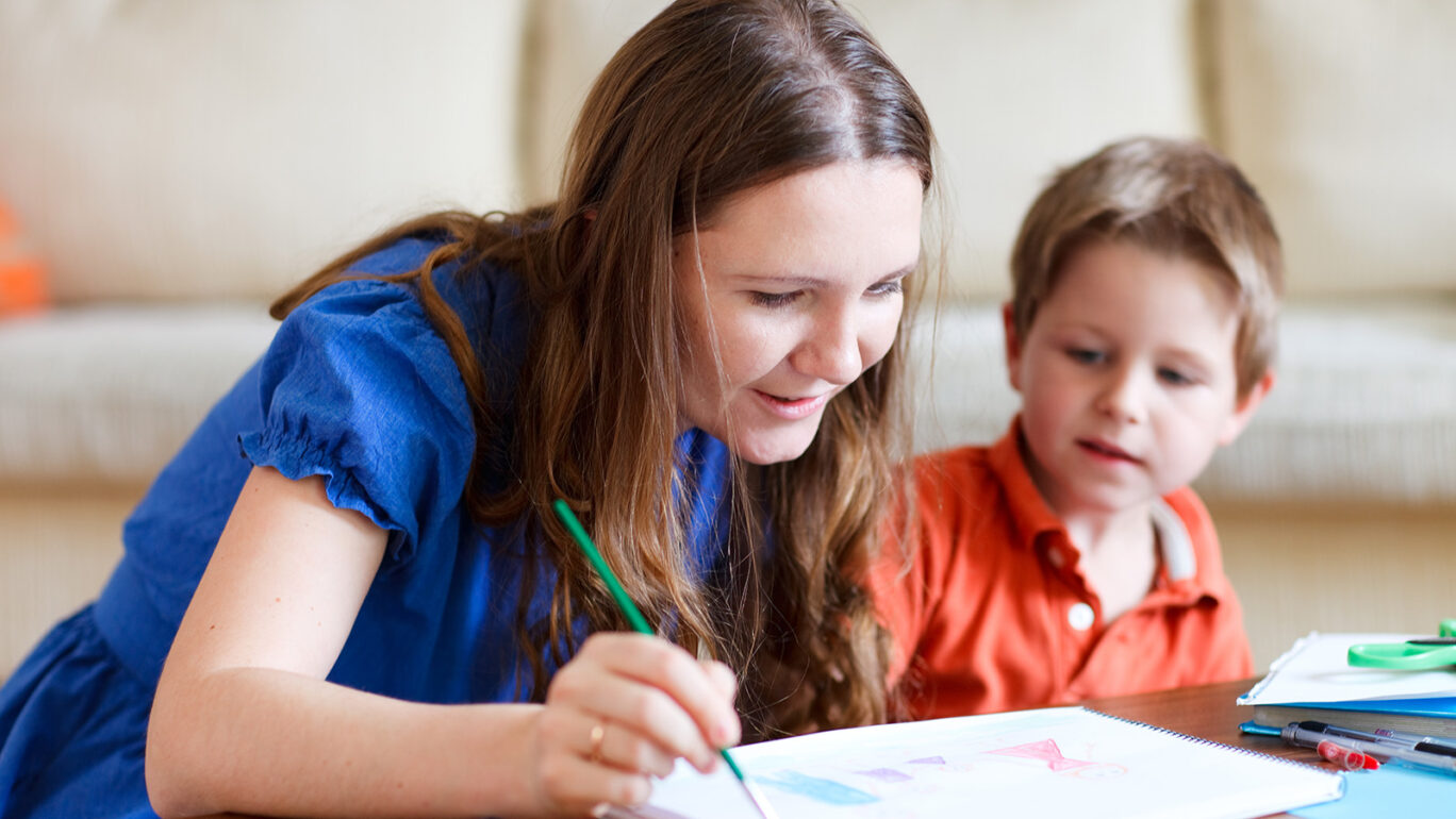 Tukiperheen äiti ja lapsi maalaavat sohvapöydään ääressä