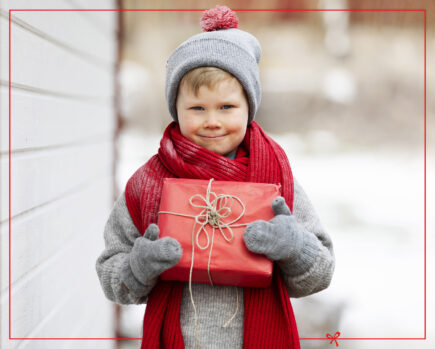 Lapsi jolla on pieni joululahja sylissään.