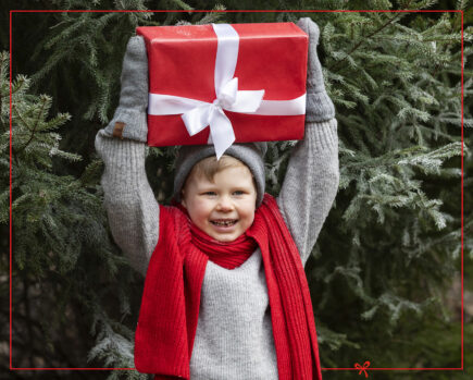 Lapsi pitää joululahjaa päänsä päällä.