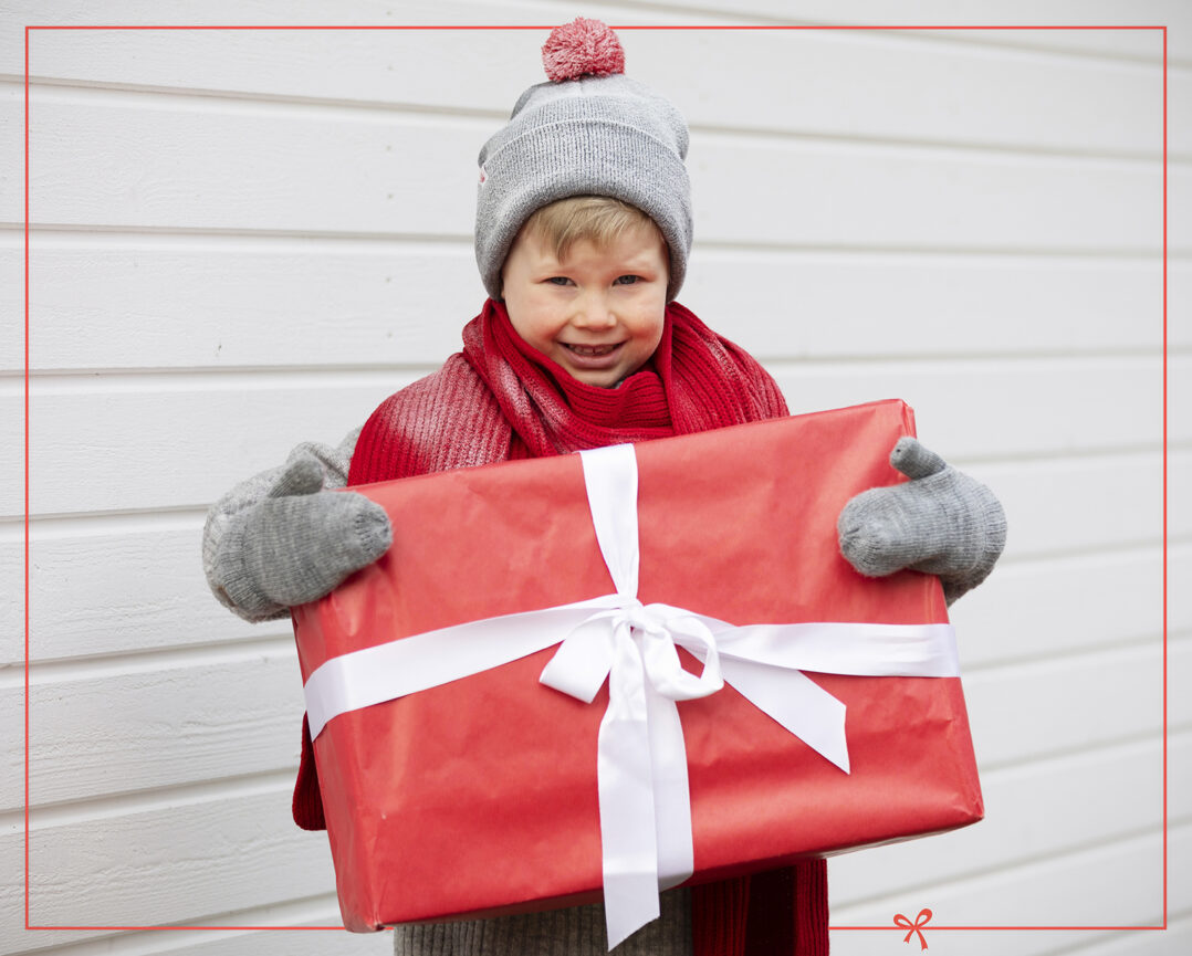 Lapsi iso joulupaketti käsissään.