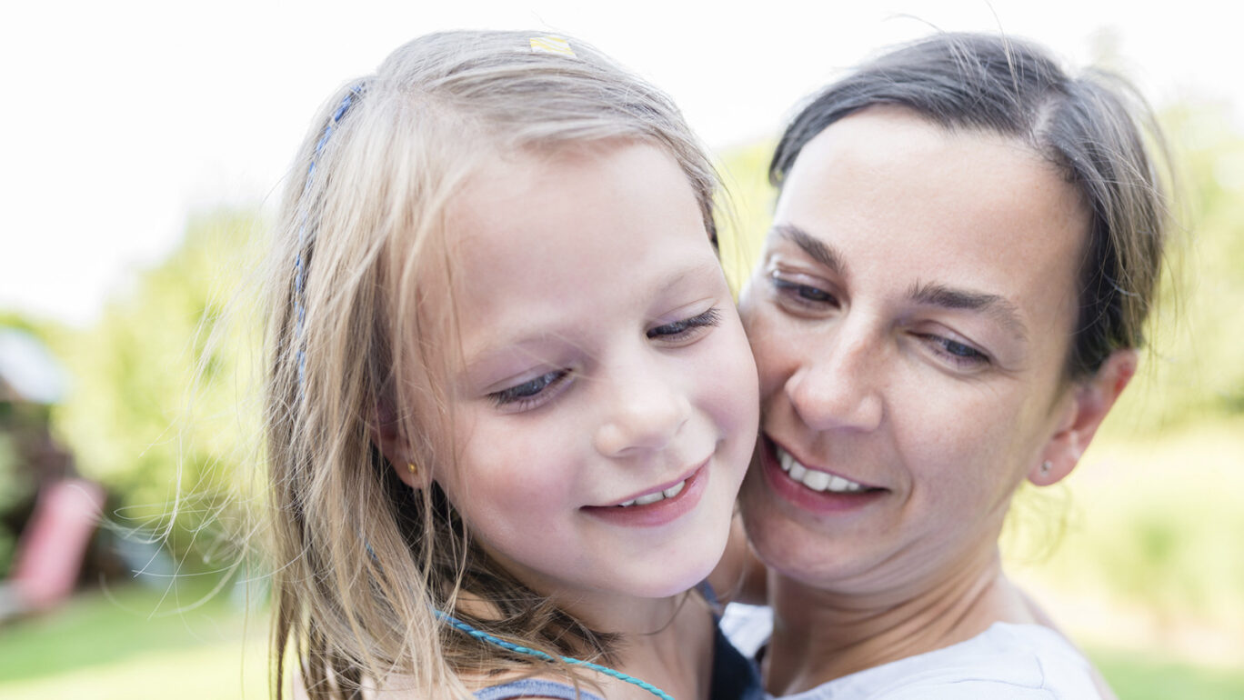 Iloinen tyttö naisen sylissä