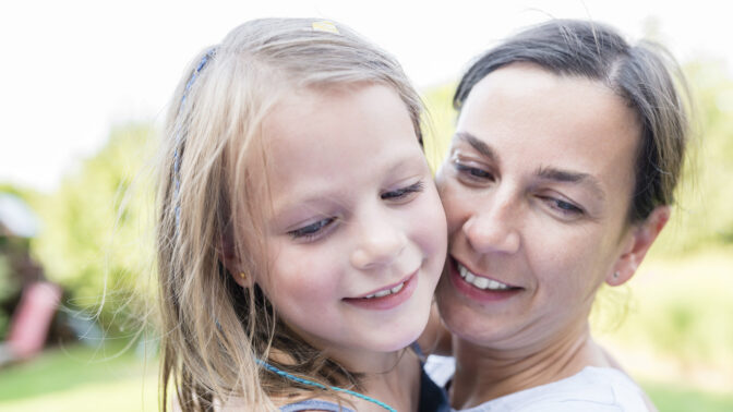 Iloinen tyttö naisen sylissä