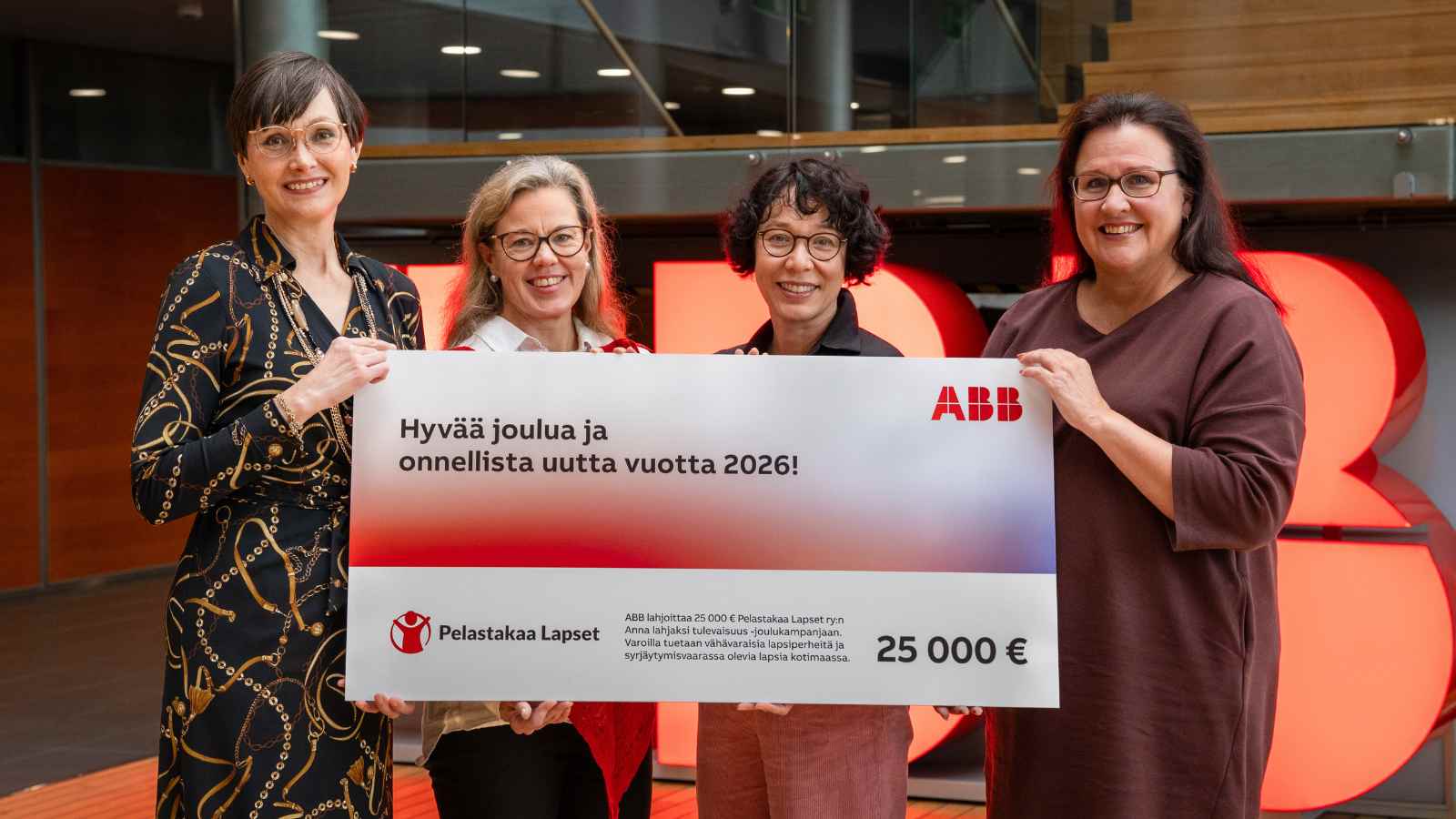 ABB:n ja Pelastakaa Lasten edustajat pitävät lahjoitusshekkiä käsissään.