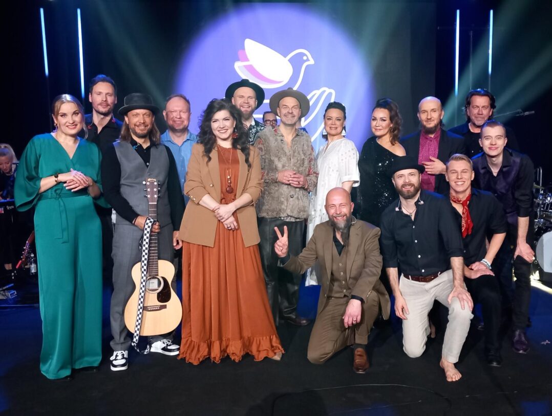 Artisteja rivissä seisomassa konserttilavalla.