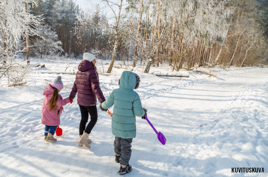 Kuvassa aikuinen ja kaksi lasta talvimaisemassa.