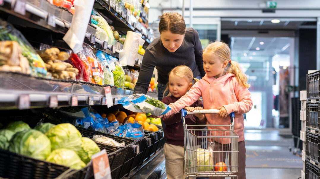 Äiti ja kaksi lasta ovat kaupan hedelmä- ja vihannesosastolla