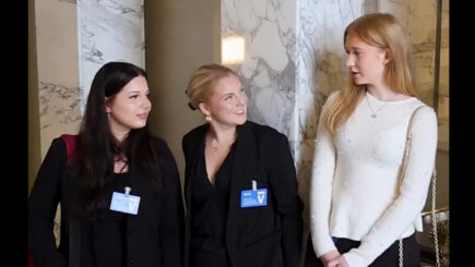 Kolme nuorta seisoo eduskuntatalon portailla