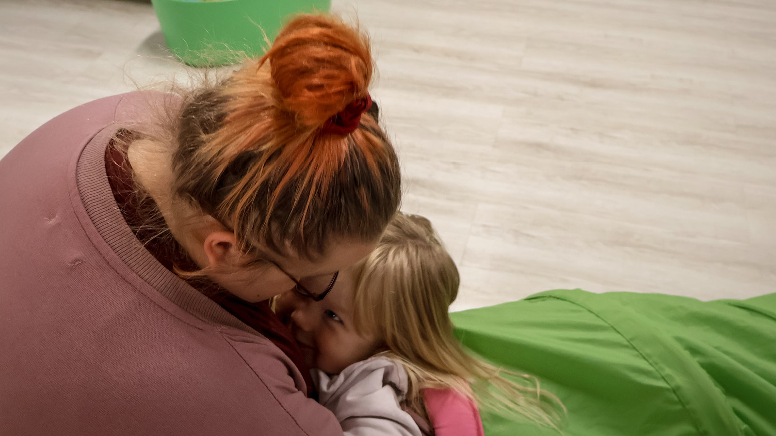 Äiti ja lapsi halaavat hymyillen toisiaan leikkipaikalla