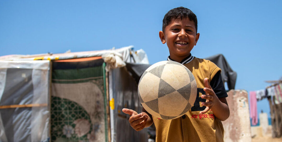 Iloinen poika jalkapallon kanssa.