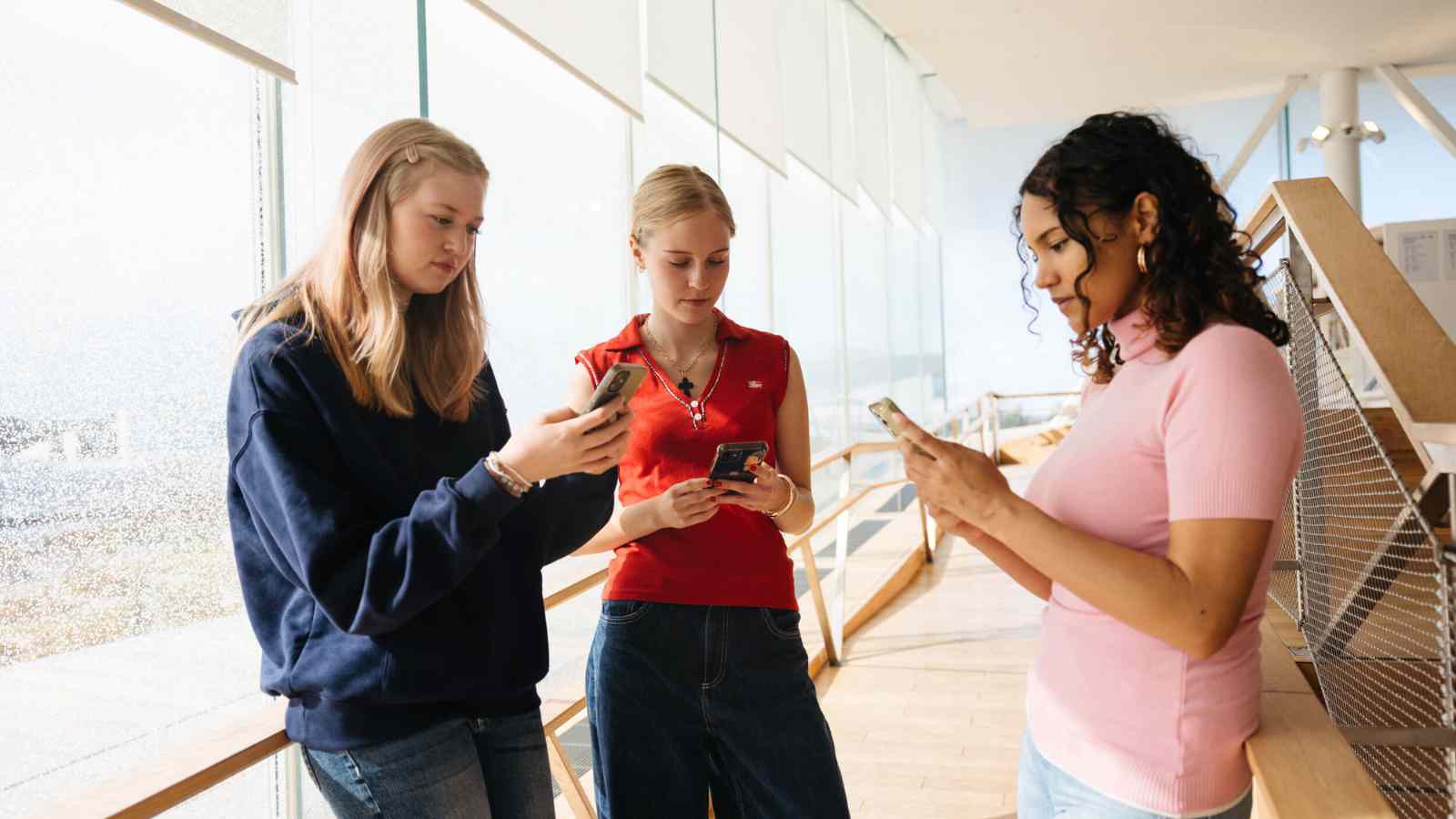 Kolme nuorta selaamassa puhelimiaan