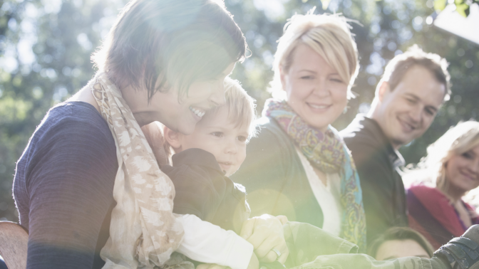 Aikuisia istumassa ulkona lapsi sylissä