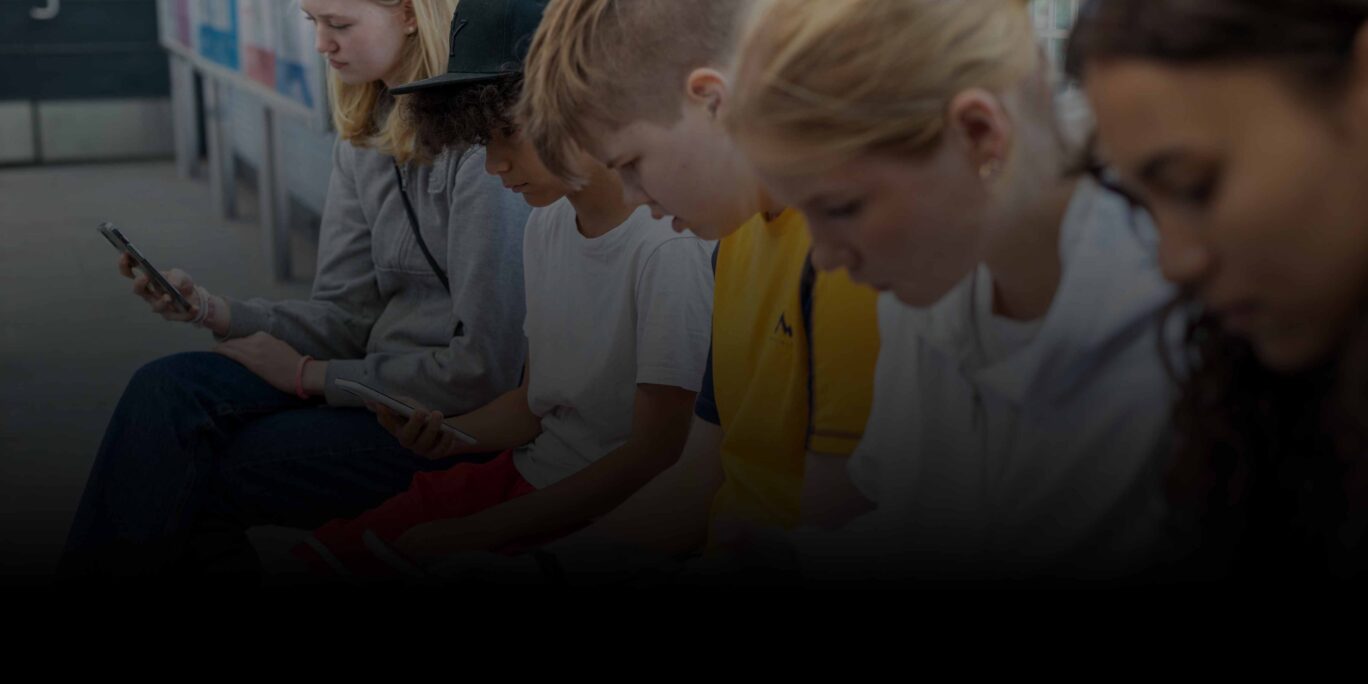 Kuvassa lapsia istuu rivissä älypuhelimet kädessään.