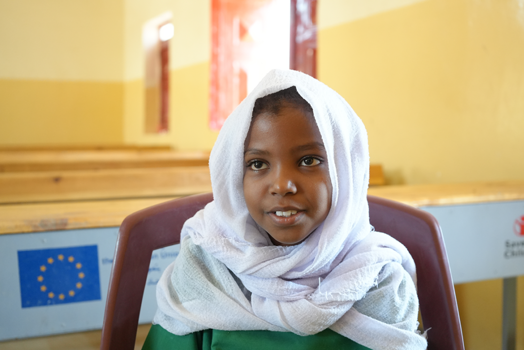 Tyttö istuu luokkahuoneessa. Taustalla EU:n logo. 