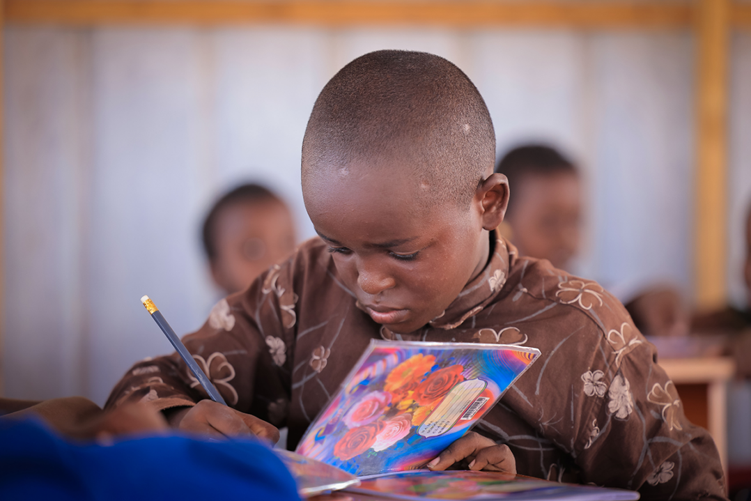 Lapsi kirjoittaa vihkoon.