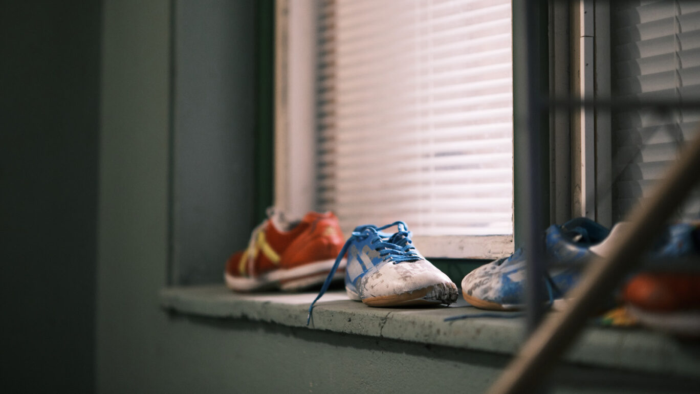 Ikkunalaudalla punainen ja kaksi sinistä jalkapallokenkää